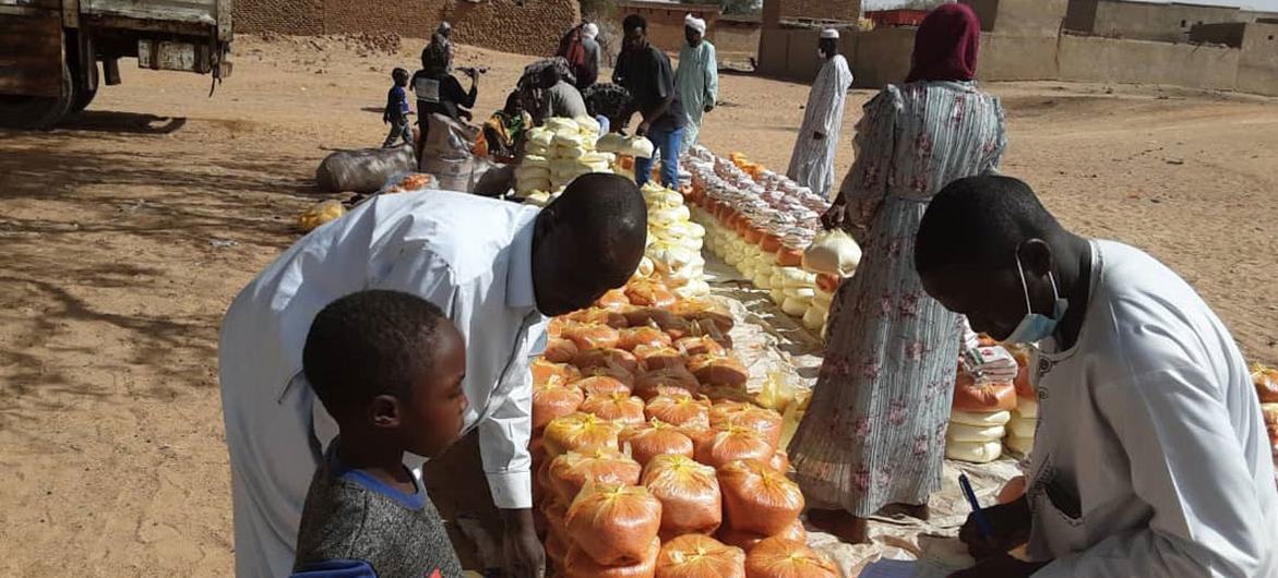 People are being handed food in an outdoor space, a young boy and an older man are featured prominently 