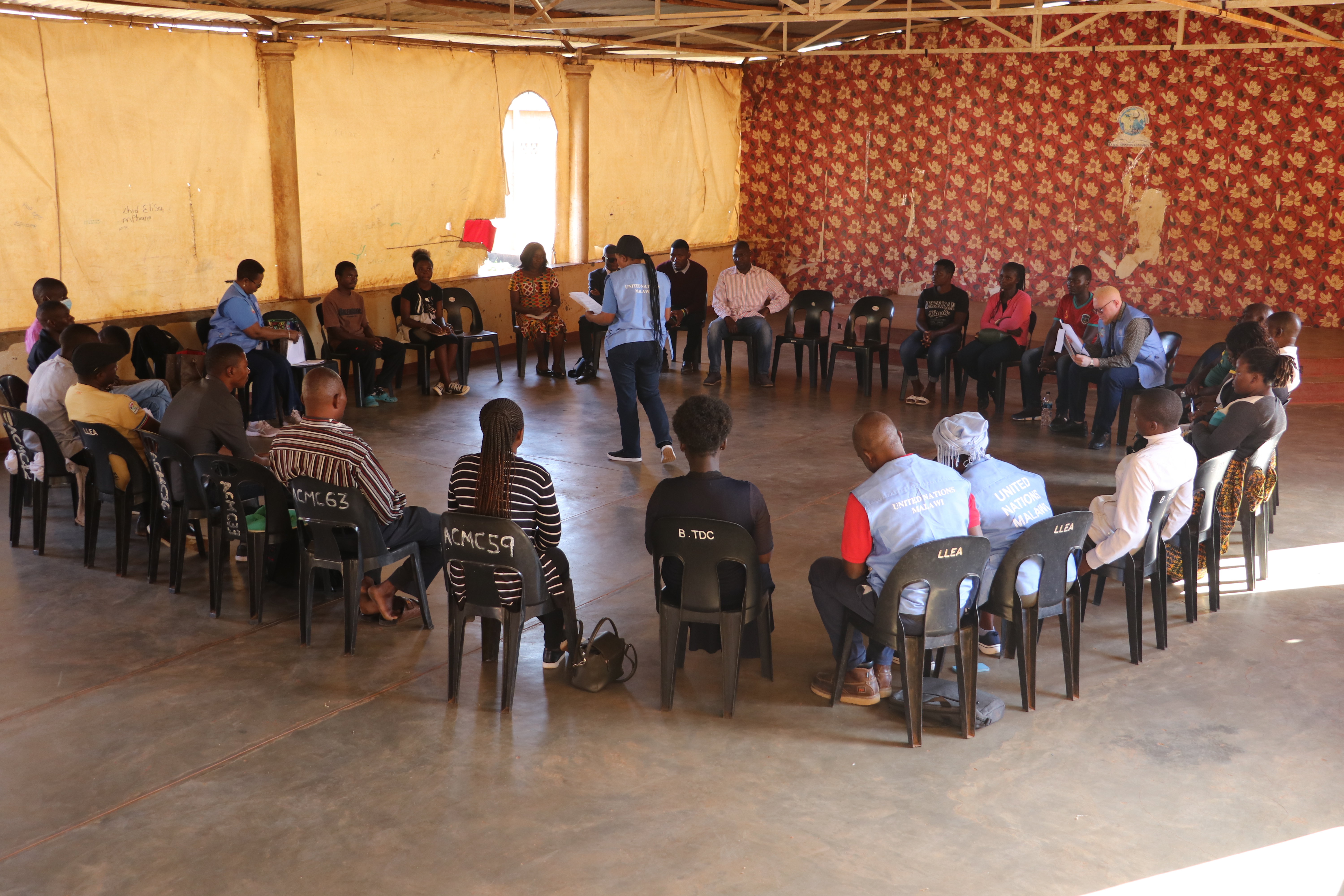 A group of people gather in a room in chairs, appearing to be in deep discussion