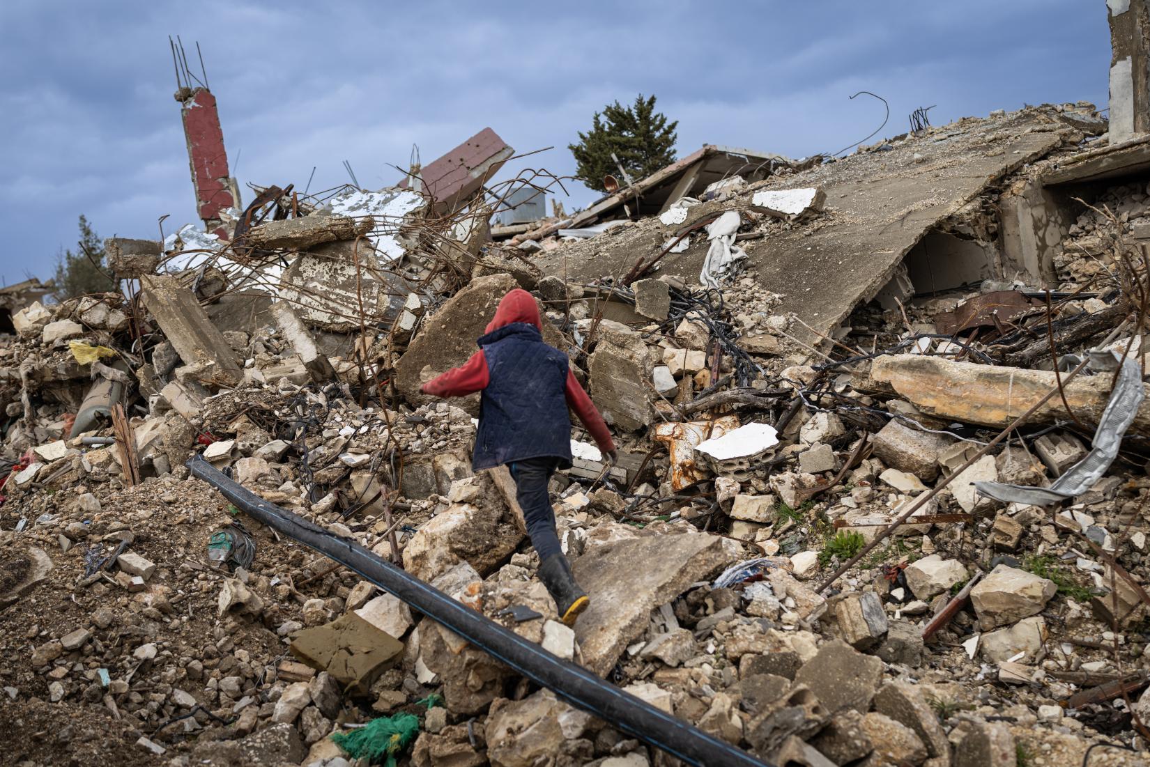 Shadi, an 11-year-old boy, walks through the ruins of Ayta al-Shaab.