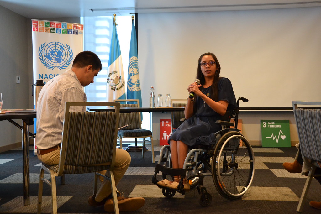 A female disability-inclusion leader speaks to a male high-level UN official during a workshop.