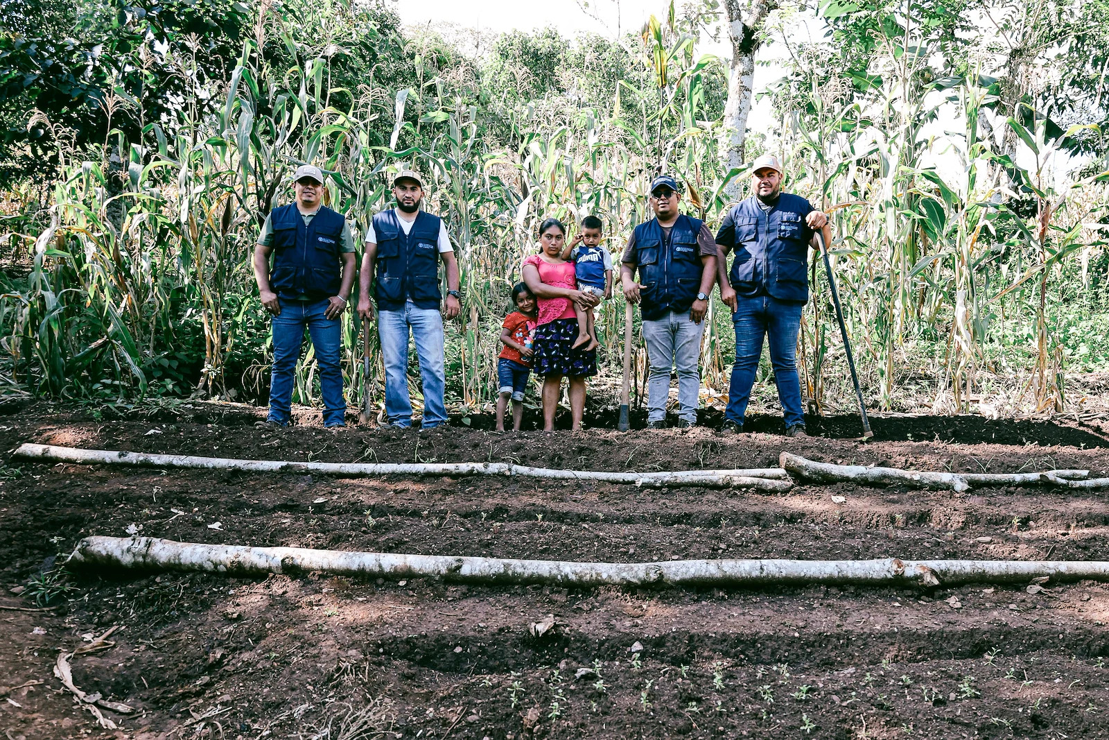 UN staff stand in a field in Guatemala with a local female farmer.