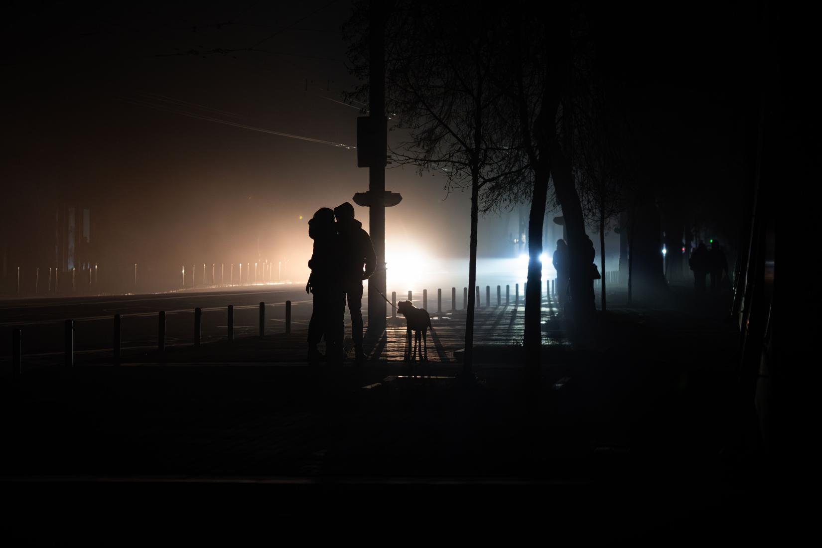 A couple in Ukraine walks their dog amid a power outage.