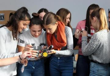 Girls look down into their hands while holding an educational tool.