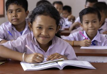 school children sit at their desks working 