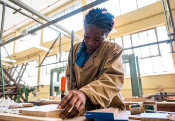 woman in beige jacket works in carpentry studio  