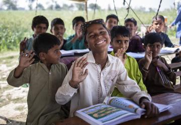 group of young school boys sit in outdoor classroom smiling at camera 
