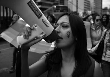 black and white photo of woman at protest speaking into a megaphone
