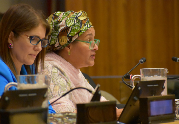woman in pink top and green head scarf speak at panel discussion 