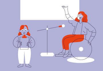 Two people in a meeting room with one presenting and using a wheelchair, and the other is a little person holding a clipboard