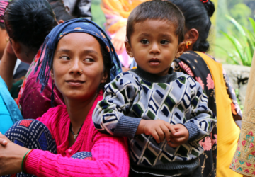 The image shows a group of people outdoors. There is child who is dressed in a striped sweater.