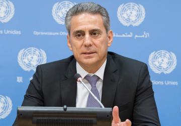 The RC sits in front of a lectern, in the background is a blue board with the UN logo