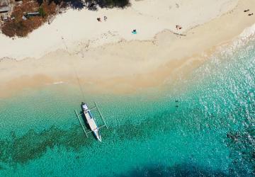 An aerial view of a serene beach setting with a sea plane in the water