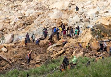 People working on landslides and gathering outside in a devastated area