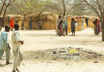 A dessert area with two children walking around in a displaced community