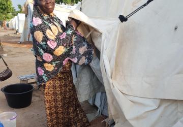Woman in traditional Ghanaian dress outside temporary housing, demonstrating UN support to displaced populations in Ghana