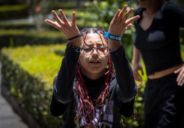 A young dancer stretches her open hands upwards.
