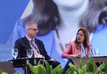 A man and a woman are speaking on a stage.