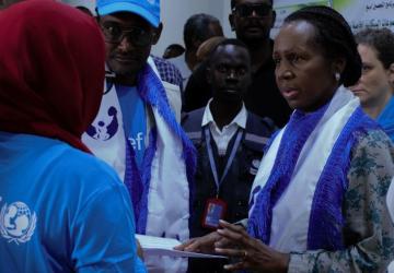 A woman is surrounded by others wearing UN branded clothing and they are all engaging in a conversation
