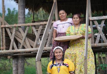Three women in an outdoor setting looking at the camera and smiling