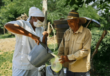 A man pours something into another bucket in an outdoor setting