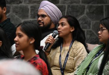 A young woman is holding a microphone and speaking to an audience