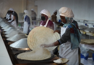 A group of women are cooking in a hot steaming room 