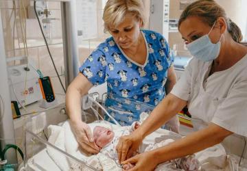 Two nurses care for a child in a NICU