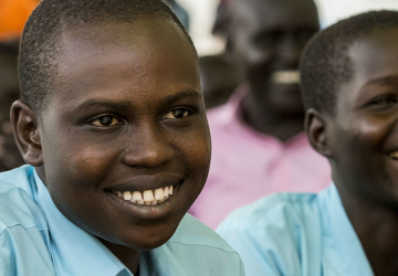 A group of children in a classroom, looking into the distance and smiling 