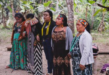 A group of women in traditional dress stand together in an outdoor setting  