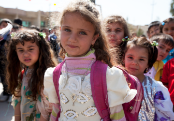 A group of young little girls looking at the camera and smiling in an outdoor setting