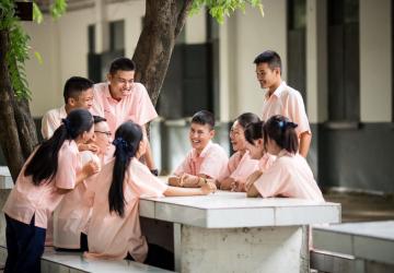 A group of young children in an outdoor setting, sitting around a table