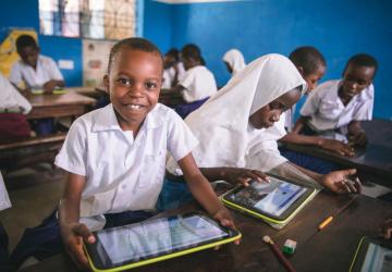 Kenyan elementary school students (male and female) using tablets in a classroom.