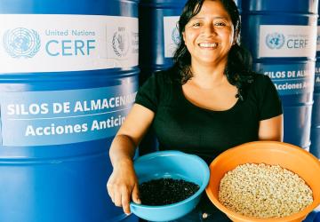 A woman in Guatemala holds two bowls of harvests she reaped.