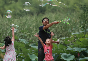 A father and his two young daughters in China play with bubbles.