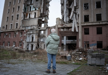 A high-level UN official surveils the damage done to a building in Ukraine.