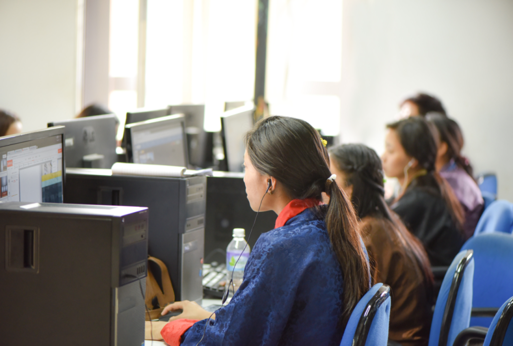 A young girl looking at a computer screen, he back is turned to the camera