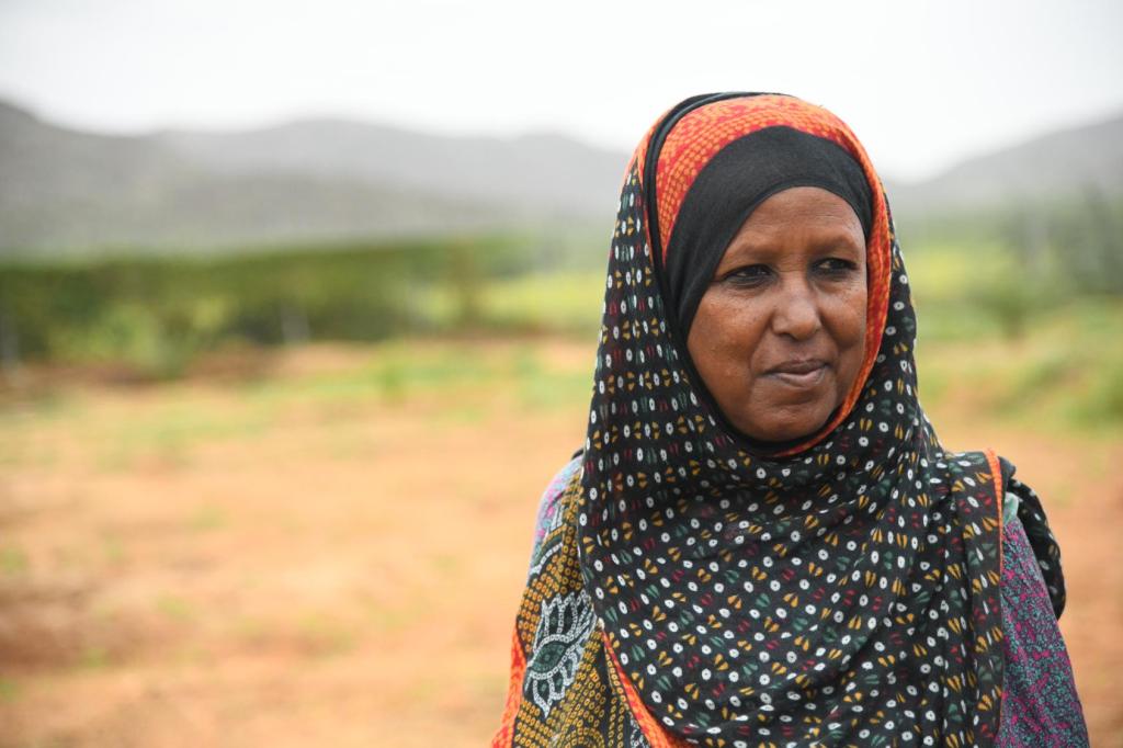 A woman is looking at the camera, she is wearing traditional dress and in an outdoor space