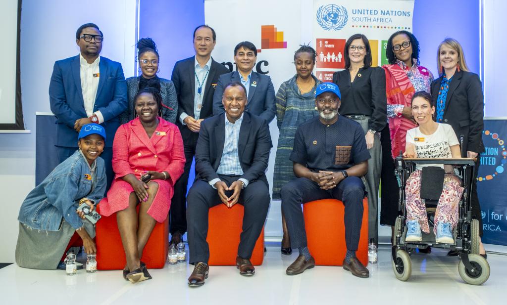 A group of people standing in front of UN branding and smiling at the camera