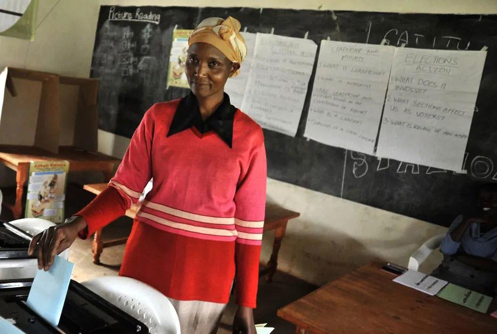 A woman casting her vote in a classroom 