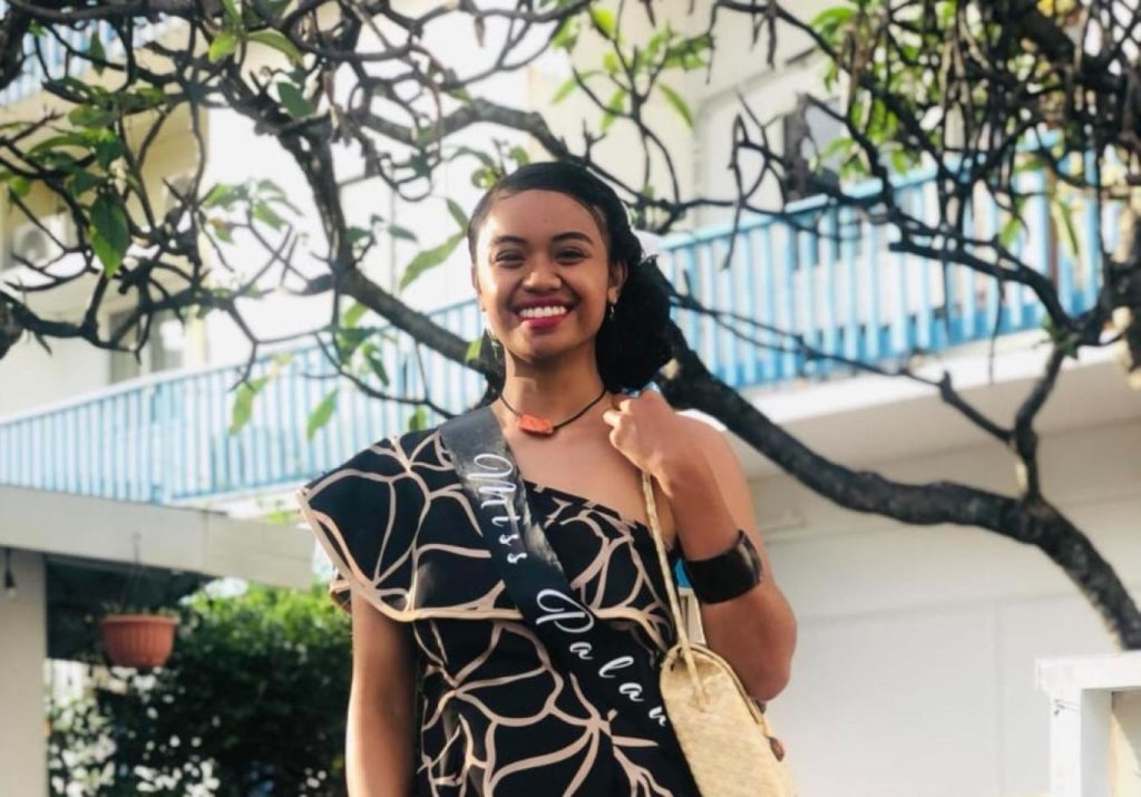 A young woman in an outdoor setting. She is smiling and looking at the camera