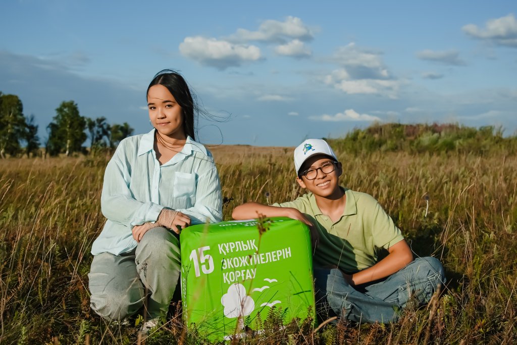 Children posing with SDG 15 cube in a wide open field.