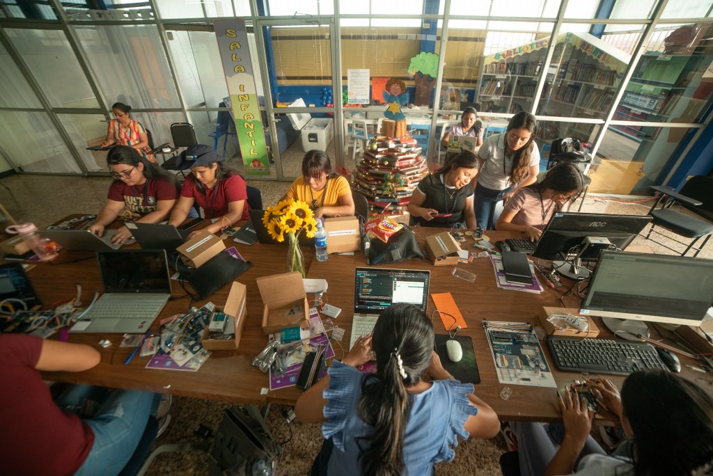 A group of women in Costa Rica sit at a table using their laptops. 