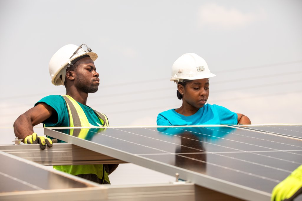A man and a woman work on a solar panel in Zimbabwe.