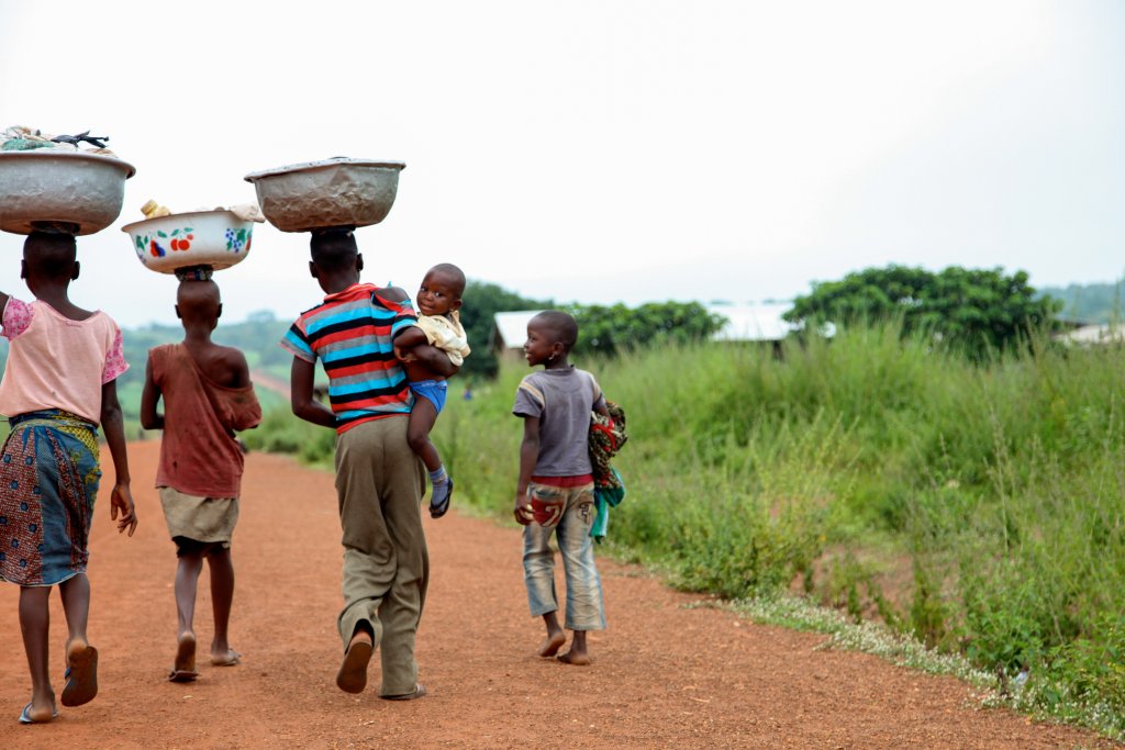 Youth in Benin walk with bowls on their heads.