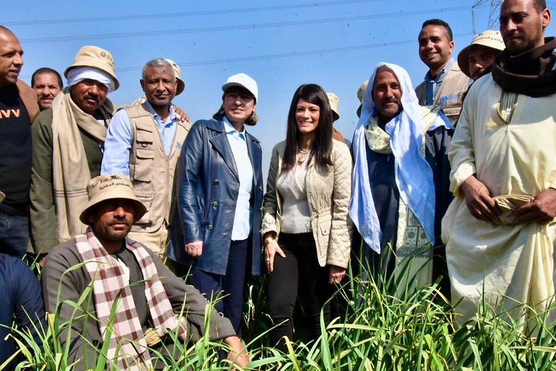 Two women in a field surrounded by community members