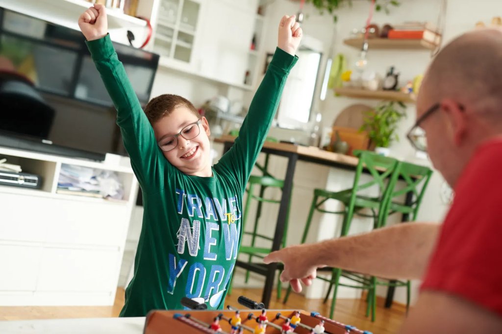 A young boy in Montenegro happily plays foosball with his father.