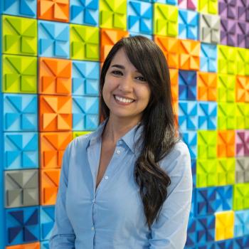 A woman smiling, wearing a baby blue shirt