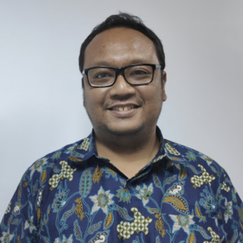 A man in a colorful shirt smiles brightly at the camera. 