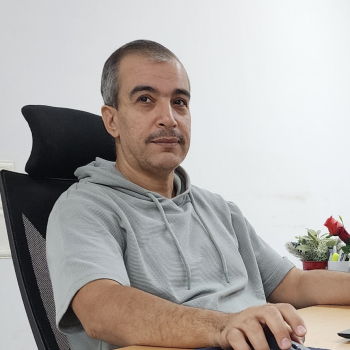 A man sits at a desk while working on his computer. 