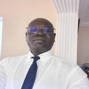 man in white shirt and navy tie looks at camera 